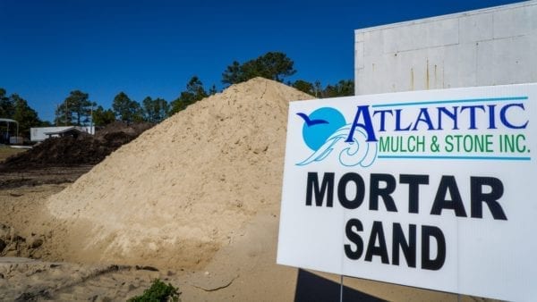 mortar sand mound with Atlantic Mulch & Stone sign to the right